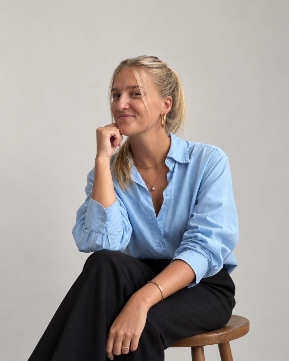 Portret van Lieke, zittend op een kruk, lichtblauw overhemd